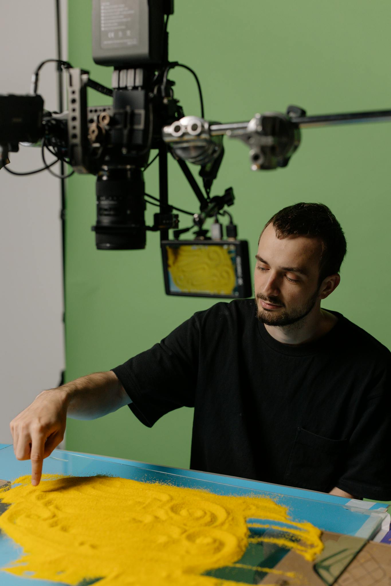 Artist working on art project with camera setup in studio.